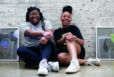 Two young black queens laughing while sitting down