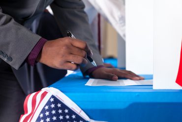 Closeup of man's hand while voting in election vote booth.